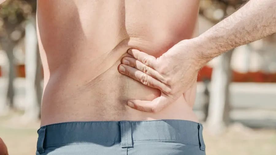 Desk-Job Lower Back Pain Stretches & Prevention Bangalore Desk-job lower back pain Bangalore — IT professional holding lumbar spine in pain, treated with McKenzie extensions, hip-hinge retraining and workplace ergonomics audit at Pro Physiotherapy JP Nagar